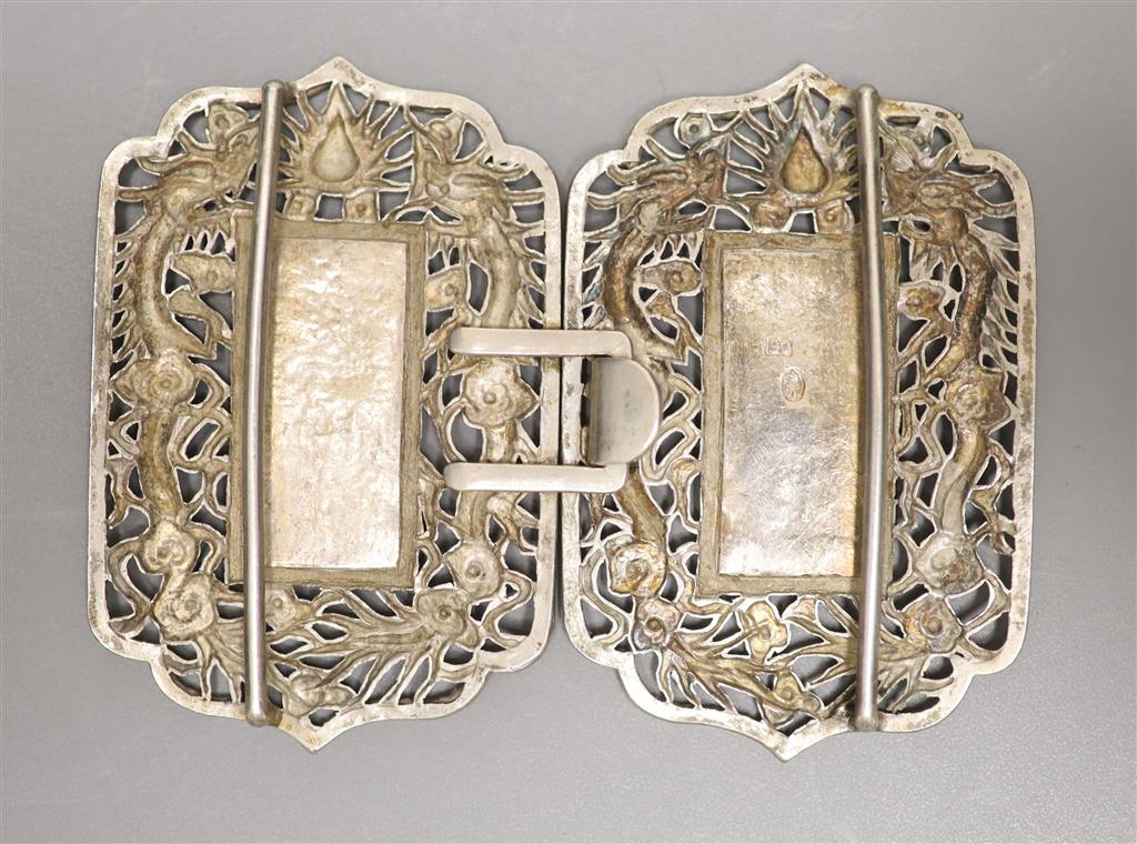 A Chinese pierced white metal nurses buckle, decorated with dragons and character marks, overall width 10.3cm.